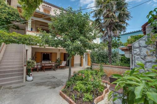 a house with a courtyard with a table and a tree at Apartment 4827-2 for 4 Pers in Nerezine in Nerezine