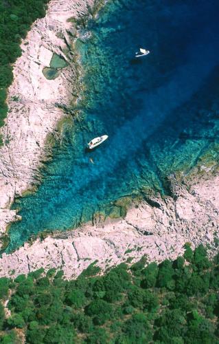 two boats in the water next to a rocky shore at Apartment 4827-2 for 4 Pers in Nerezine in Nerezine