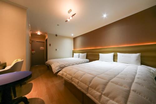 1 dormitorio con 2 camas con almohadas blancas y escritorio en Gyeongju bulgooksa W Drive-in Motel, en Gyeongju