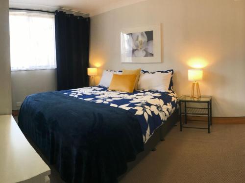 a bedroom with a bed with a blue comforter and two lamps at Aviemore 4 14 Cobbodah Street in Jindabyne