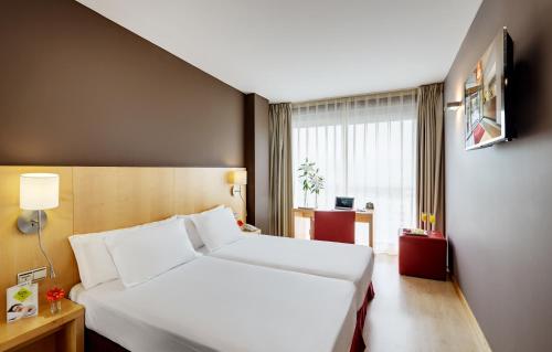 una camera d'albergo con un letto bianco e una finestra di Hotel Sercotel Portales a Logroño
