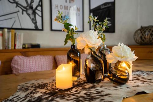 a table with three vases with flowers and a candle at Ferienhof Homann Sauerland in Brilon