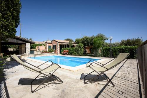 a pair of chairs sitting next to a swimming pool at Karrua House - Magnolia Room in Modica