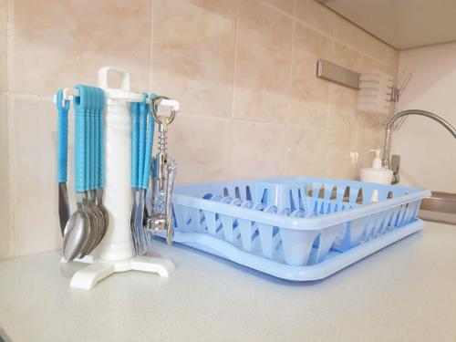 a kitchen counter with a blue dish drying rack and utensils at Шикарная Двухкомнатная in Atyraū