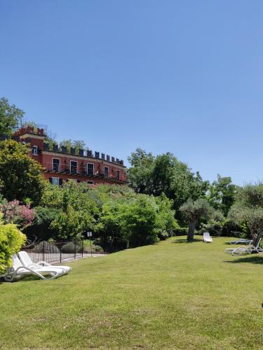 a park with lawn chairs and a building in the background at Hotel Castello S. Antonio in Lazise