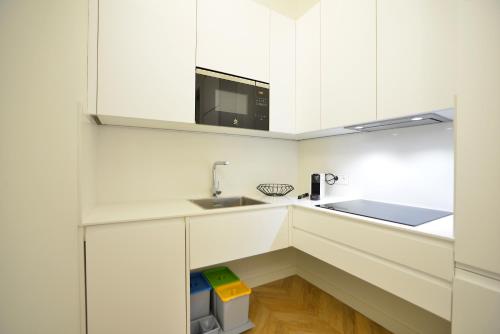 a white kitchen with a sink and a microwave at Plaza Mina Suites - Adults Recommended by Luxury Suites Cadiz in Cádiz