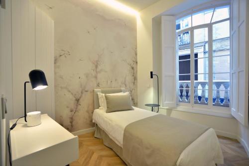 a white bedroom with a bed and a window at Plaza Mina Suites - Adults Recommended by Luxury Suites Cadiz in Cádiz