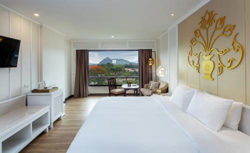 una habitación de hotel con una gran cama blanca y una ventana en The Riverie by Katathani SHA Extra Plus, en Chiang Rai