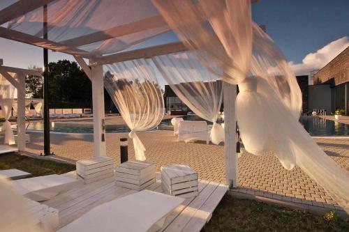 a white pavilion with white curtains and a pool at Termy Warmińskie in Lidzbark Warmiński