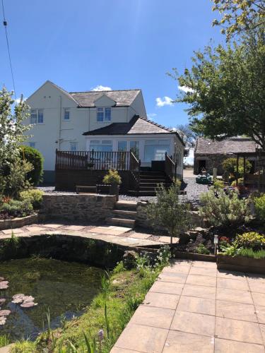 a house with a pond in front of a house at Frongaer Bed And Breakfast in Llanerchymedd