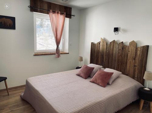 Schlafzimmer mit einem großen Bett mit einem Kopfteil aus Holz in der Unterkunft Le cocon d’Emma in La Bresse