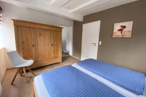 ein Schlafzimmer mit einem blauen Bett und einem weißen Stuhl in der Unterkunft Das alte Zollhäuschen in Bad Laasphe