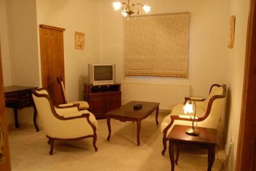 a living room with chairs and a table and a tv at Vengera Suites in Galata