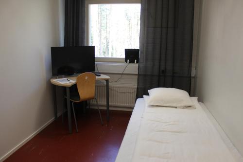 a small room with a bed and a desk with a computer at Metsäkartano in Kannus