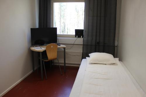 Habitación pequeña con cama y escritorio con ordenador. en Metsäkartano, en Kannus