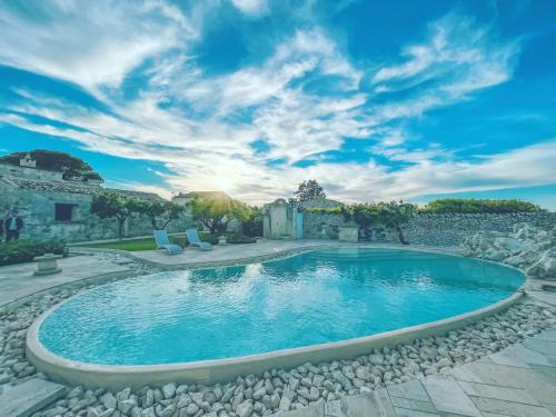 una piscina en un patio con 2 sillas alrededor en Relais Masseria Capasa, en Martano