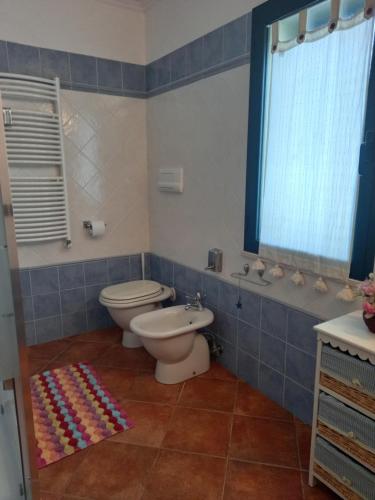 a bathroom with a toilet and aicolored rug at Appartamento in zona residenziale in Orosei