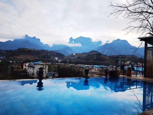 a swimming pool with mountains in the background at Tujia folk houses in Zhangjiajie