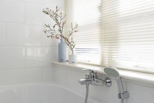 a white bathroom with a sink and a window at Stylish Canalhouse A in Amsterdam