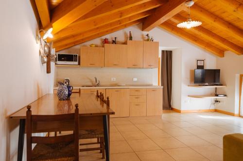 uma cozinha com armários de madeira e uma mesa com cadeiras em Albergo Diffuso Polcenigo Casa Rigo em Polcenigo