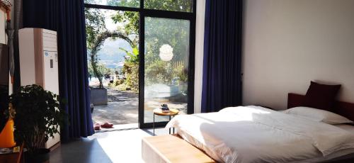 um quarto com uma cama e uma grande porta de vidro em Tujia folk houses em Zhangjiajie