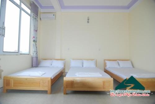 two twin beds in a room with windows at Nhà nghỉ Dương Vũ in Mộc Châu