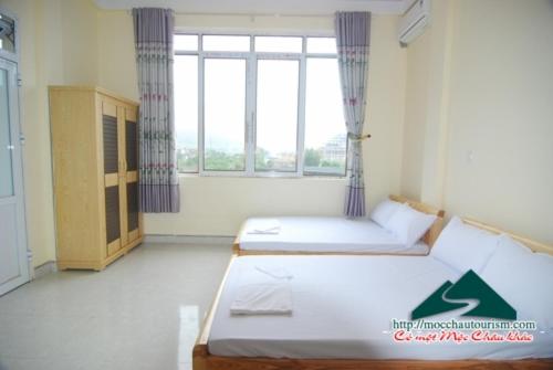 2 Betten in einem Zimmer mit einem großen Fenster in der Unterkunft Nhà nghỉ Dương Vũ in Mộc Châu