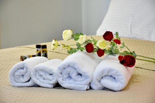 a group of towels on a bed with roses at The Blue Rooms in Áyioi Apóstoloi