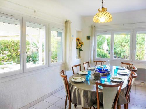 a dining room with a table with chairs and windows at Holiday Home Les Vives by Interhome in Narbonne-Plage