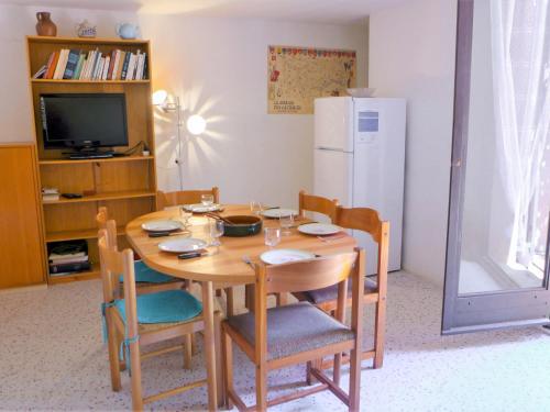 - une table à manger avec des chaises et un réfrigérateur blanc dans l'établissement Holiday Home Les Romarines-6 by Interhome, à Gruissan