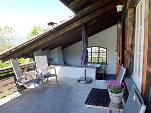 eine Terrasse mit Stühlen, einem Tisch und einem Sonnenschirm in der Unterkunft Chalet Panoramablick by Interhome in Aeschi