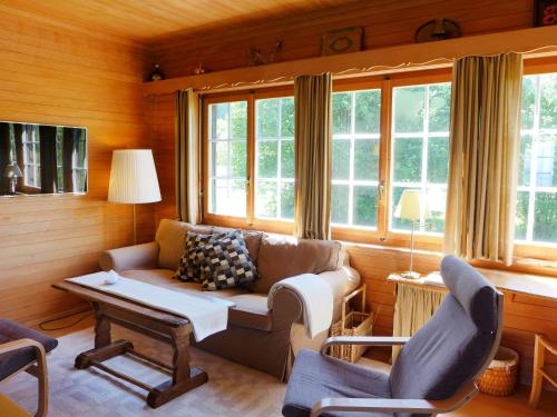 a living room with a couch and chairs and windows at Chalet Panoramablick by Interhome in Aeschi
