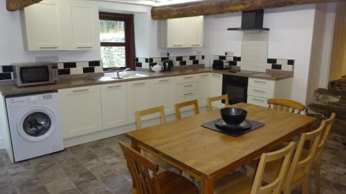 a kitchen with a wooden table and a dining room at Blaentwrch Farmhouse in Llanddewi-Brefi