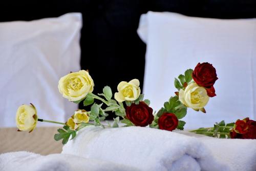 a bouquet of yellow and red roses on a bed at The Blue Rooms in Áyioi Apóstoloi