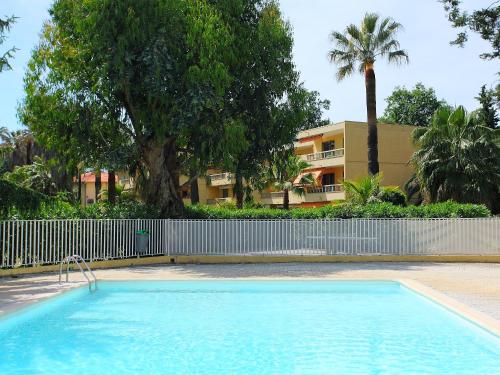 una piscina frente a un edificio con palmeras en Apartment Les Eucalyptus by Interhome, en Golfe-Juan