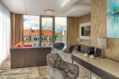 a living room with a desk and chairs and a large window at Grand Focus Hotel Szczecin in Szczecin