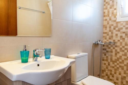 a bathroom with a sink and a toilet and a mirror at Fotis Apartments in Artemida