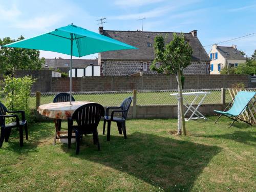 a table and chairs and a blue umbrella in a yard at Holiday Home La Corvette by Interhome in Pléneuf-Val-André