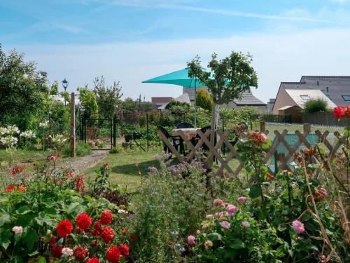 a garden with flowers and a fence with an umbrella at Holiday Home La Corvette by Interhome in Pléneuf-Val-André