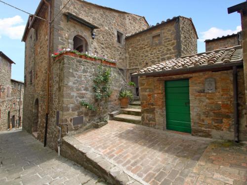 a brick building with a green garage door at Apartment Taverna by Interhome in Montecatini Val di Cecina