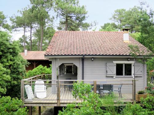 a house with a deck with two chairs on it at Holiday Home L'Escouarte - MAU170 by Interhome in Maubuisson