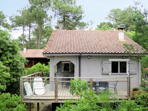 a house with a deck with two chairs on it at Holiday Home L'Escouarte by Interhome in Maubuisson