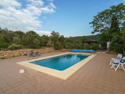 a swimming pool with two lawn chairs and a table at Holiday Home Forest by Interhome in Benitachell