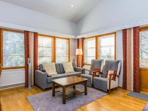 a living room with a couch and chairs and windows at Holiday Home Karhunvartijan pirtti c4 by Interhome in Ruka