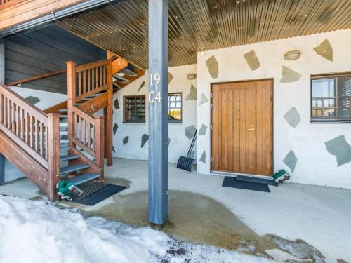 een huis met een houten deur in de sneeuw bij Holiday Home Vuosselinkulma 4 by Interhome in Ruka