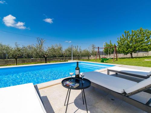 a pool with a table and a bottle of wine next to it at Holiday Home Vera by Interhome in Sveti Ivan