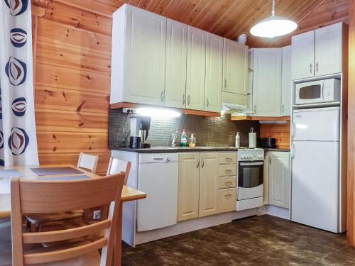 a kitchen with white appliances and wooden cabinets at Holiday Home Rovarakka 1 a by Interhome in Levi