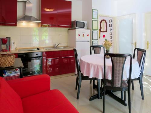a kitchen with red cabinets and a table and a red couch at Apartment Stella - CKV300 by Interhome in Bribir