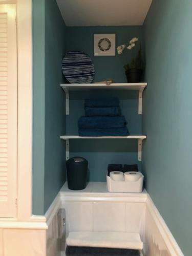 a bathroom with blue walls and white shelves with towels at Dana Villa Holiday Accommodation in Oban