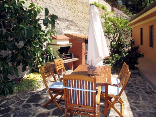 una mesa de madera con una sombrilla blanca en el patio en Holiday Home Irma by Interhome, en Cipressa